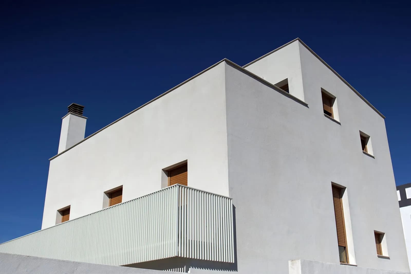 After: Minimalist white house against a clear blue sky
