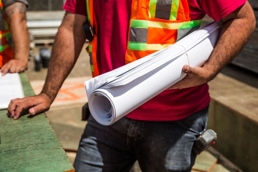 Site worker holding rolled blueprints